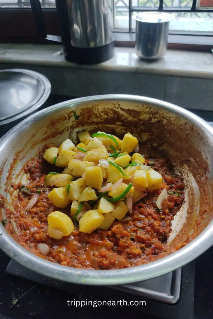 aloo bhuna, add onion capsicum masala and potatoes in the gravy