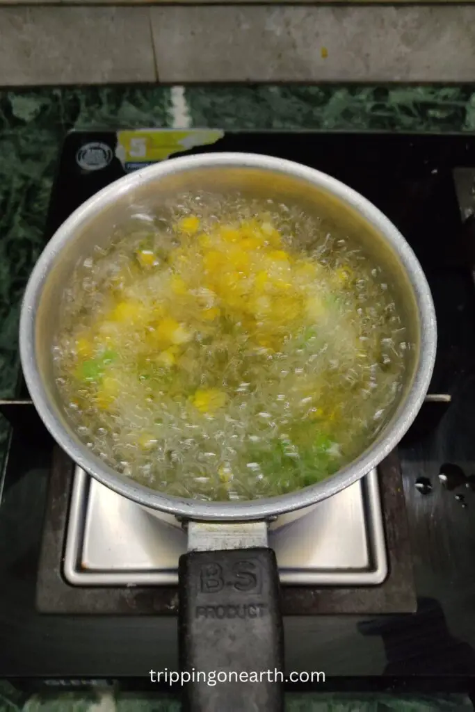 corn and peas boiling in a pan