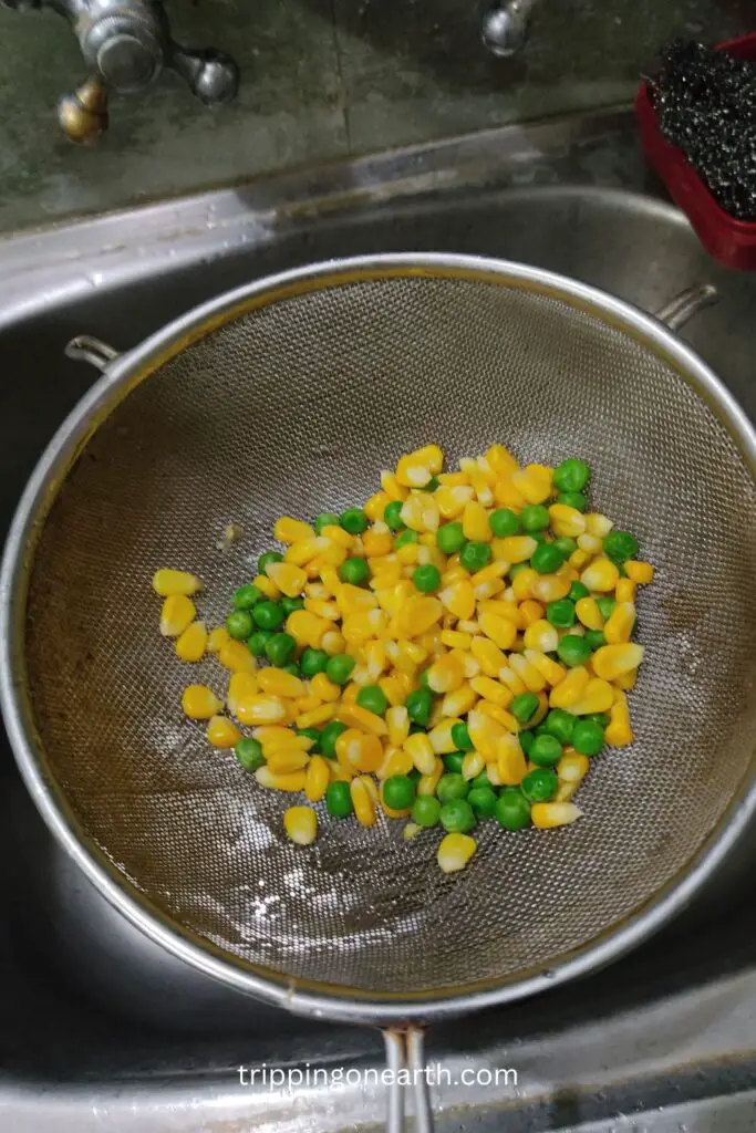 corn and peas on a strainer