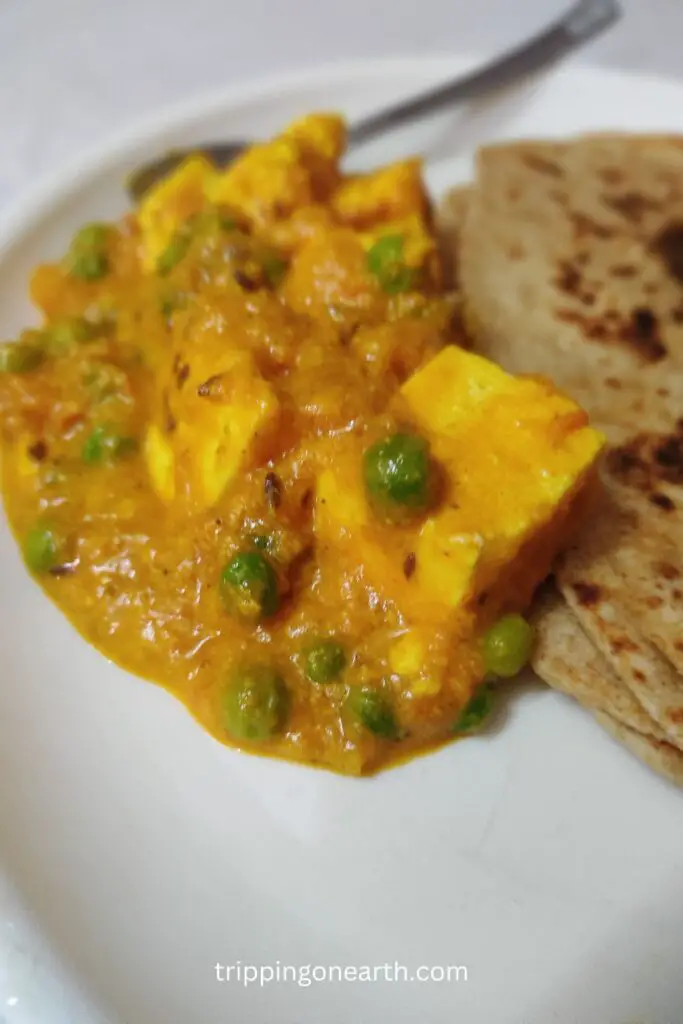 matar paneer without onion and garlic on a plate along with parathas