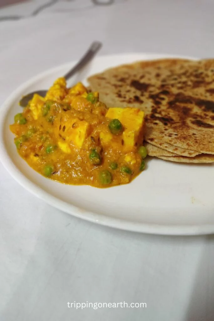matar paneer without onion and garlic on a plate along with parathas