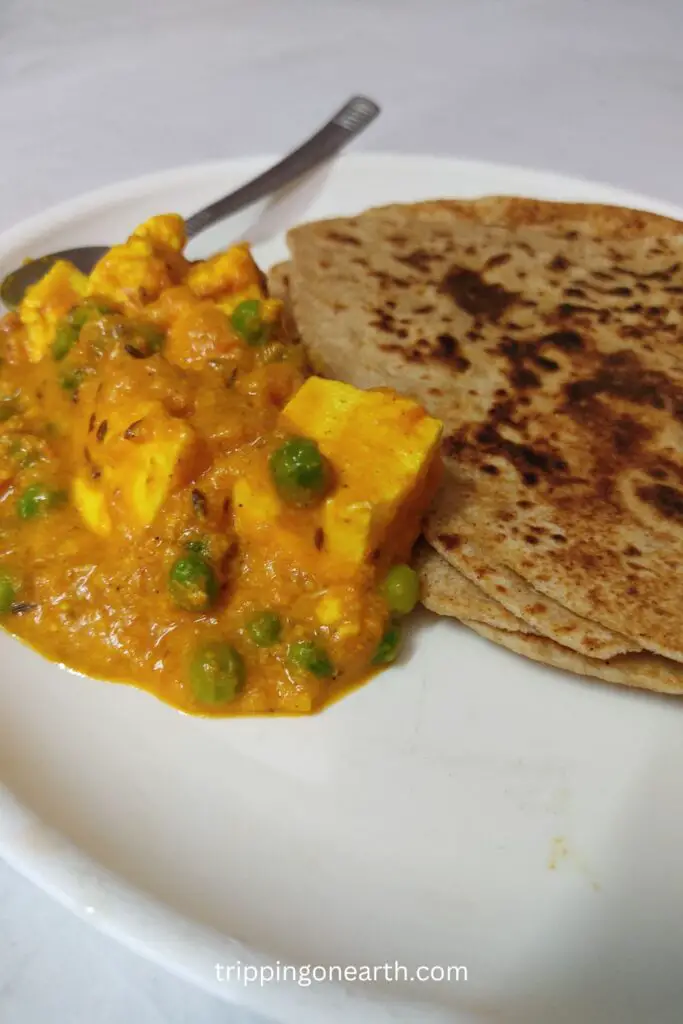 matar paneer without onion and garlic on a plate along with parathas