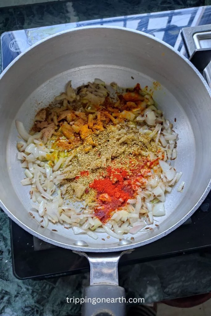 powdered spices on onions in a skillet