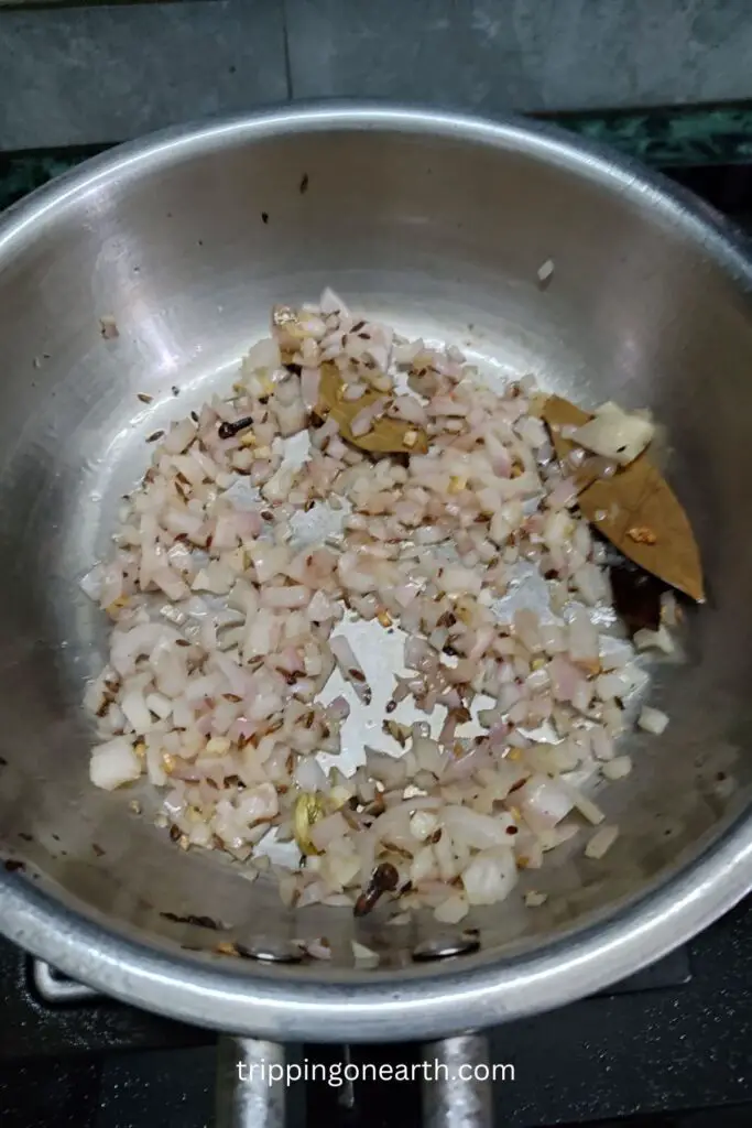 fried brown onions in a pan along with whole spices