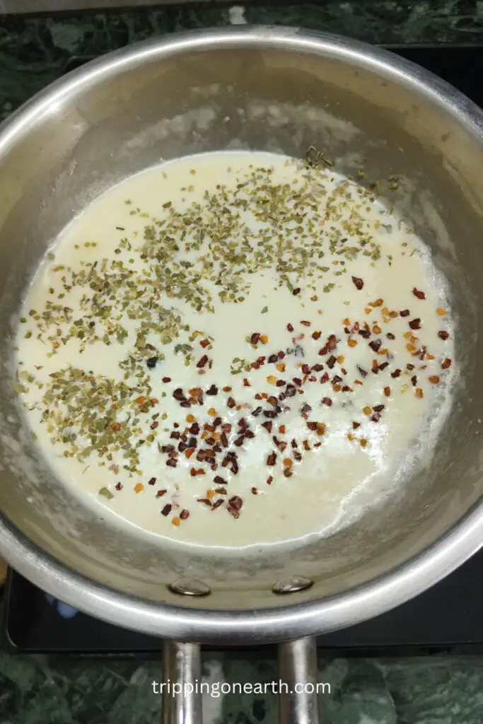 milk in the skillet topped with oregano and red chili flakes