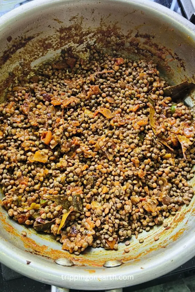 kali masoor dal mixed with onion tomato mixture in the pan