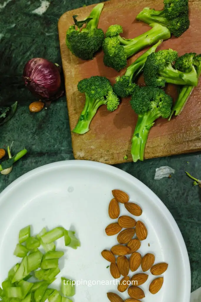 Broccoli florets on a chopping board, and almonds with chopped broccoli stems on a white plate