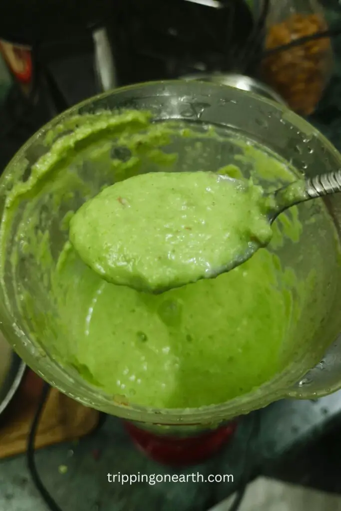 Broccoli mixture paste on a spoon and grinder in the background