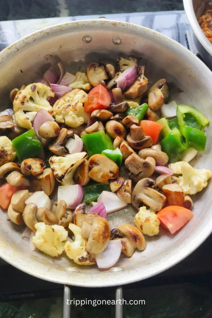 seared cauliflower, mushrooms, capsicum, onions, and tomatoes in a skillet