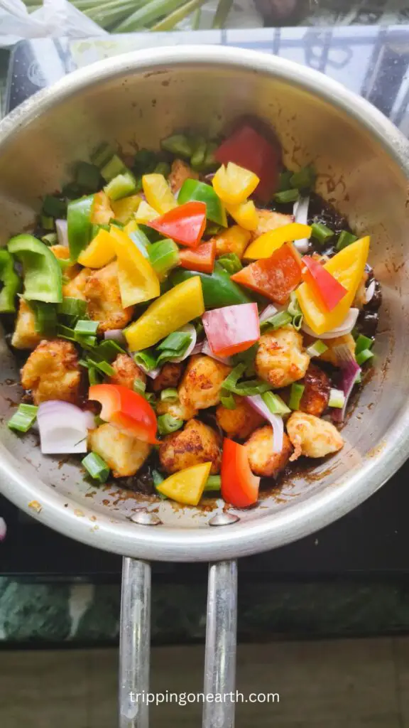 diced veggies and fried paneer in the skillet with the sauce