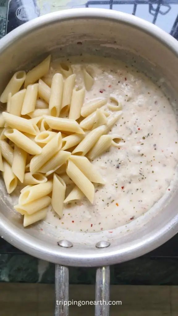 penne on one side and alfredo sauce on the other side in a skillet