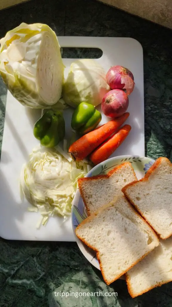 Ingredients laid out in a white chopping board: Coleslaw, capsicum, onions, carrots, and bread