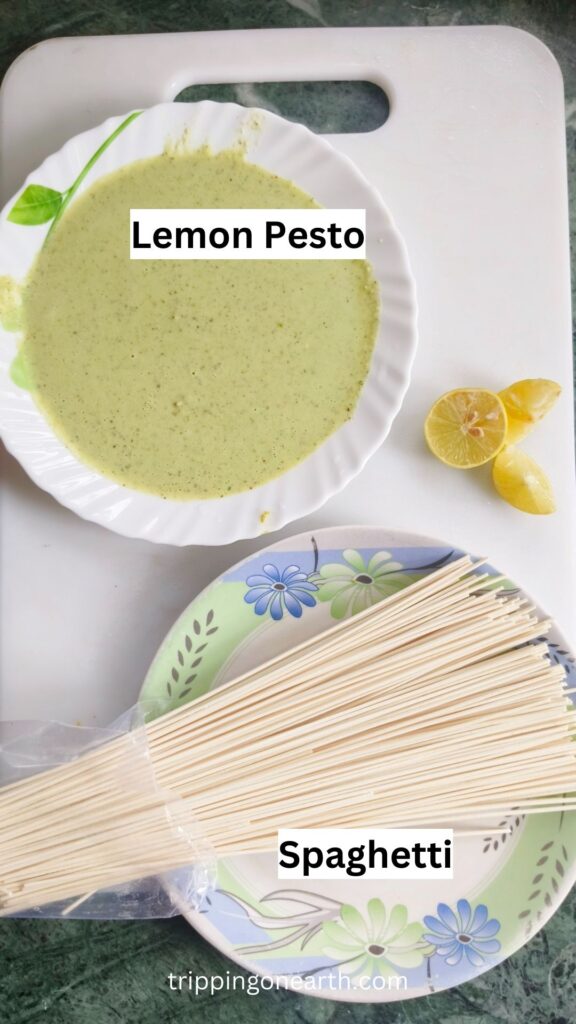 ingredients laid out in a white chopping board: spaghetti pasta and lemon pesto.
