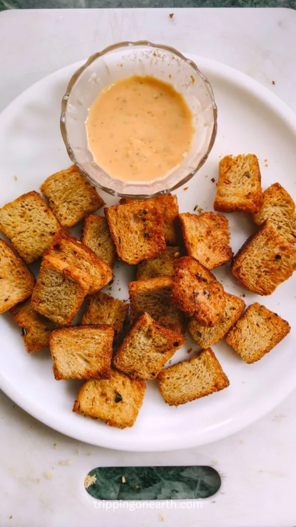 Air fryer croutons on a white plate with a dipping sauce on the side