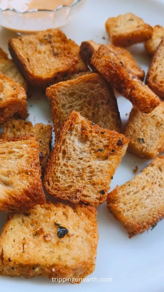 Air fryer croutons on a white plate with a dipping sauce on the side
