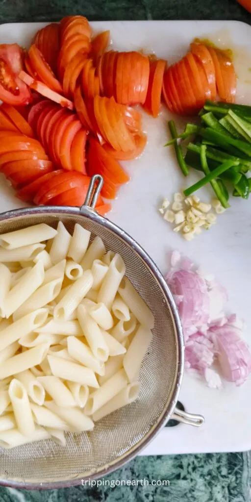 Cooked pasta resting beside chopped veggies