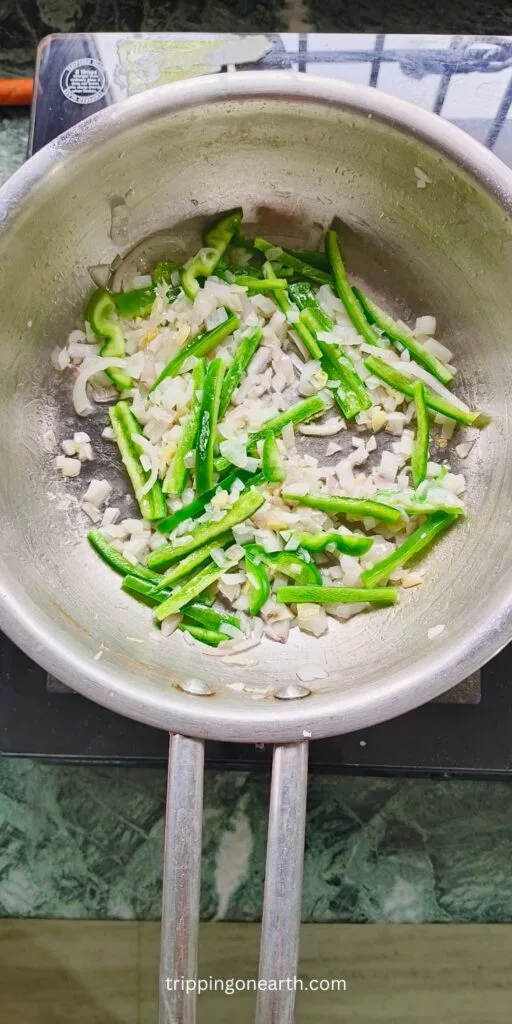 Sauteed onions, garlic, and capsicum in a skillet.